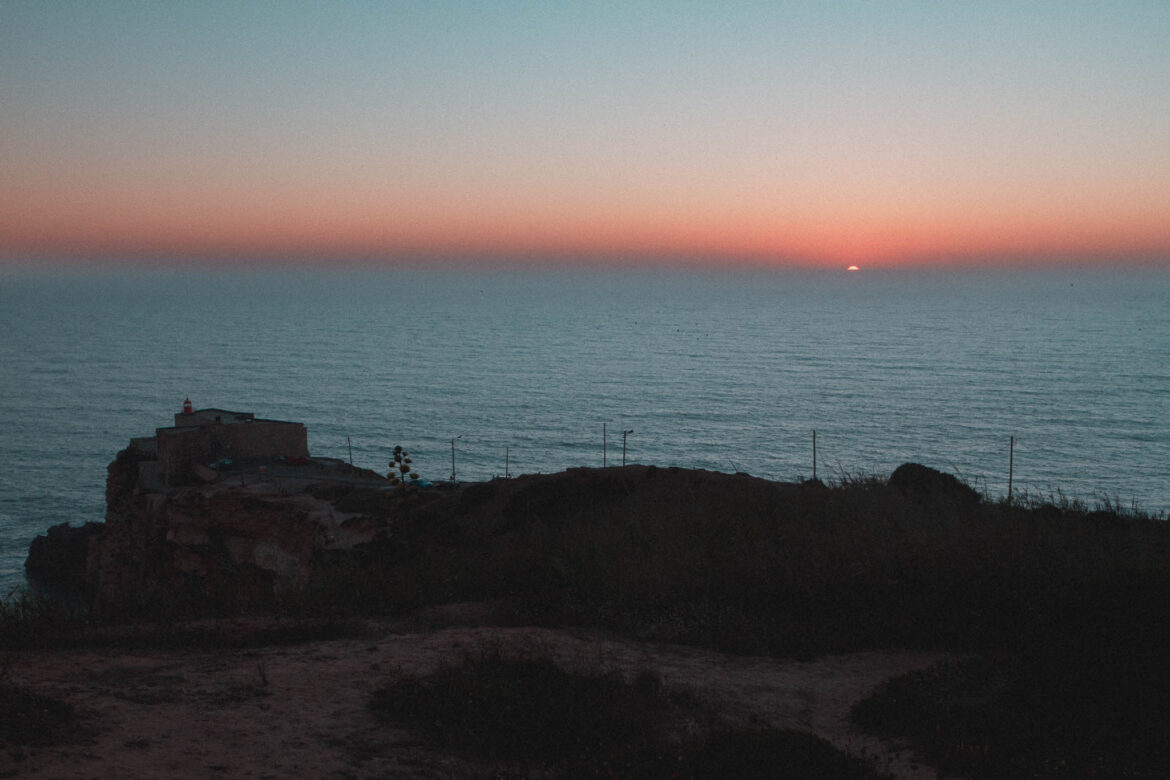 Atardecer con luz dorada con el océano atlántico desde Faro de Nazaré en penumbra. Cercano a Praia do Norte (Portugal)
