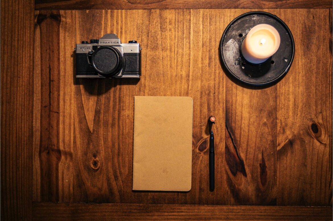 Fotografía cenital de una libreta y una cámara analógica sobre una mesa, representando el método y la planificación anual para proyectos de fotografía y vídeo